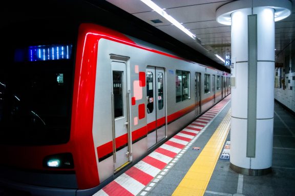 Red and silver train waiting at a modern subway station platform.