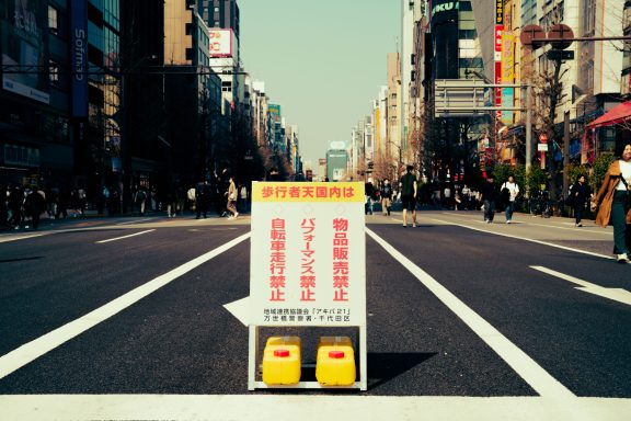 Street sign blocking traffic on a bustling city road with pedestrians in the background.