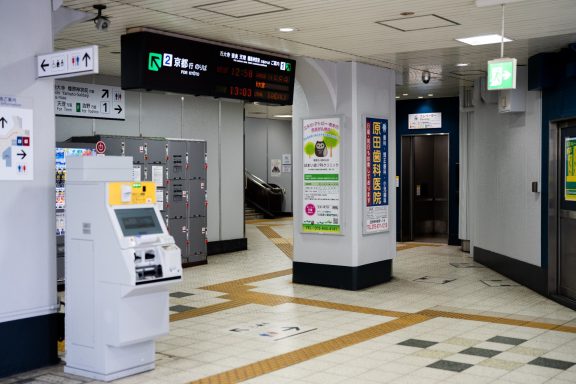 Interior of a station featuring lockers, ticket machines, and signs for directions.