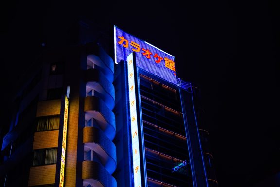 A brightly lit building at night with neon signage in Japanese.