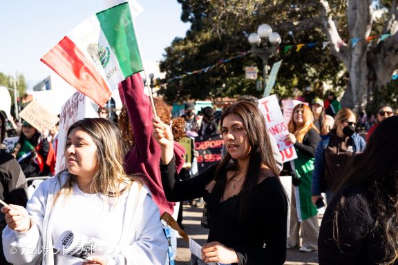 Women holding flags and signs during a lively protest in a public space.
