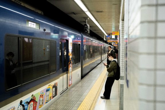 Person waiting at a subway station with a train approaching on the platform.